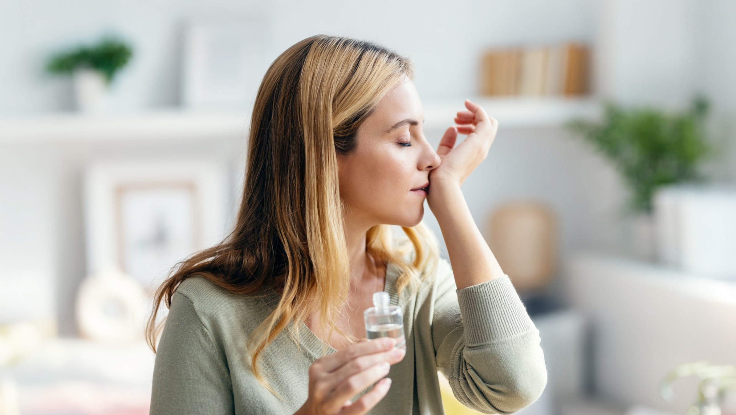 一位神情放鬆的女性閉眼嗅吸掌心的精油